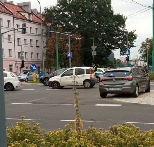 Samochody na skrzyżowani, widoczny radiowóz i policjant.