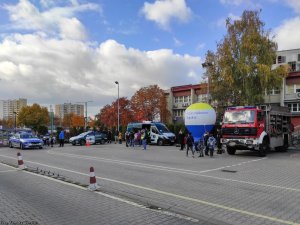 Na zdjęciu plac Wojewódzkiego Ośrodka Ruchu Drogowego w Tychach. Widoczny wóz straży pożarnej, inspektoratu transportu drogowego, radiowóz policyjny pomiędzy nimi osoby.