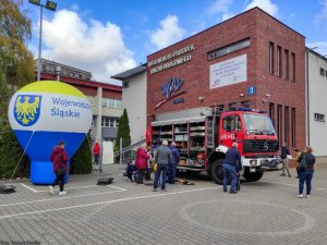 Przed budynkiem Wojewódzkiego Ośrodka Ruchu Drogowego, wóz strażacki obok osoby.