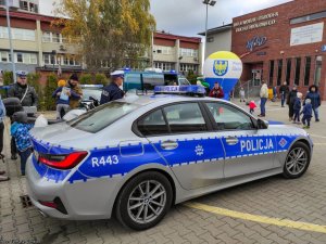 Policyjny radiowóz dalej policjanci i uczestnicy festynu.