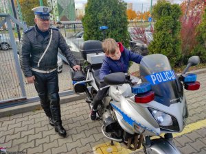 Policjant obok motocykla na którym siedzi chłopiec.