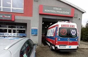 Radiowóz i karetka przed stacją diagnostyczną.