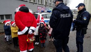 Na zdjęciu widoczni umundurowani policjanci, mikołaj dzieci oraz radiowóz.