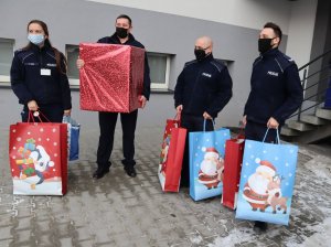 Umundurowani policjanci trzymają torby prezentowe.