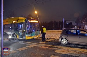 Na zdjęciu widoczny policjant, trolejbus, jest ciemno.