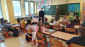 Policjant rozmawia w klasie z dziećmi na temat bezpiecznych ferii.