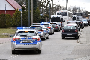 Policyjne radiowozy oraz samochody osobowe w rejonie stadionu.