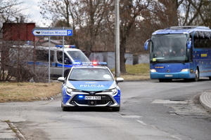 Dwa policyjne radiowozy, za nimi autobus.