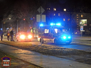 Karetka pogotowia na miejscu potrącenia pieszej, samochód osobowy, jest ciemno.