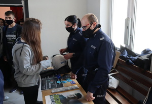 Umundurowany policjant i policjantka rozmawiają z młodzieżą.