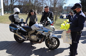 Na zdjęciu widoczni policjanci, policyjny motocykl i dziewczyna, która na niego siada.