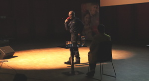 Umundurowany policjant przemawia przez mikrofon na scenie.