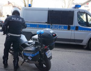 Policjant, motocykl i radiowóz.