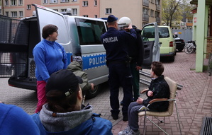 Osoby z niepełnosprawnością, opiekunka i policjant, który pomaga założyć jednej osobie hełm.