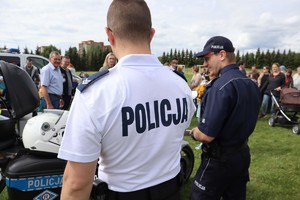 Policjant z ruchu drogowego oraz z prewencji, w tle widoczni uczestnicy pikniku.