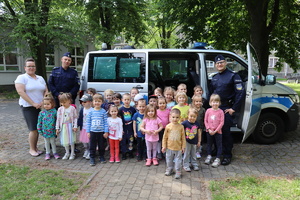 Ustawieni do zdjęcia grupowego opiekunka z dziećmi oraz policjanci, za nimi radiowóz.