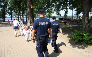 Policjanci idą za grupą dzieci, kierując się w stronę jeziora.
