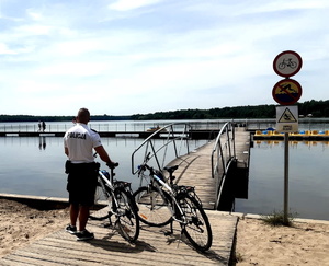 Policjant stoi przy rowerze na brzegu jeziora Paprocany.