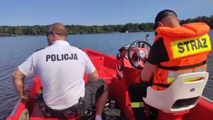 Zdjęcie przedstawiające policjanta oraz strażaka płynących łodzią ratunkową.