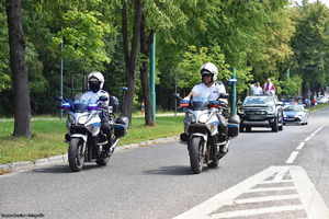 zdjęcie funkcjonariuszy Policji na motocyklach przed samochodem, na którym stoi Biskup święcący pojazdy