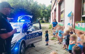 Policjant pokazuje dzieciom policyjny radiowóz.