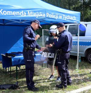 Na zdjęciu widoczni umundurowani policjanci oraz chłopiec, który założył hełm oraz trzyma policyjną tarczę.