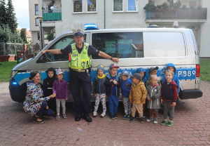 Zdjęcie grupowe policjanta z Wydziału Ruchu Drogowego z grupą dzieci oraz opiekunką.