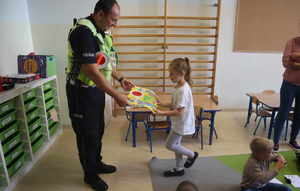 Policjant odbiera podziękowanie od dziewczynki.