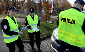 uczennice klasy mundurowej i policjant w odblaskowych kamizelkach.