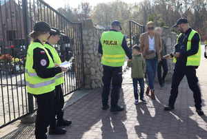 Policjanci oraz uczennice klasy mundurowej w rejonie cmentarza rozdają odblaski.