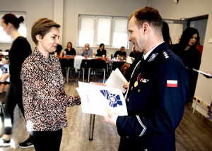 Zastępca Komendanta Miejskiego Policji w Tychach wręcza kobiecie życzenia z okazji Święta Służby Cywilnej.