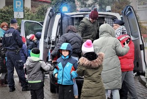 Dzieci oglądają radiowóz, policjanci stoją obok.
