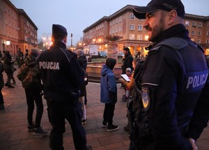 Na zdjęciu dwóch umundurowanych policjantów. Wokół nich dzieci i dorosli.