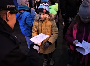 Na zdjęciu umundurowana policjantka wręczająca dziecku Elementarz Bezpieczeństwa.