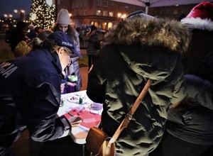 Na zdjęciu umundurowana policjantka przy stole. Na stole wstążki i dekoracje do tworzenia bombek.