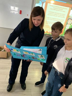 Na zdjęciu umundurowana policjantka odbierająca plakat od dzieci.