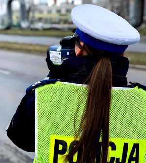 Policjantka w odblaskowej kamizelce mierzy prędkość.