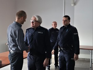 Na zdjęciu mężczyzna oraz trzech umundurowanych policjantów. Jeden z policjantów ściska dłoń mężczyzny.