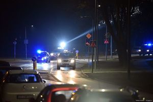 Na zdjęciu policyjne radiowozy z włączonymi sygnałami błyskowymi, które biorą udział w zabezpieczeniu przejścia kibiców na stadion.