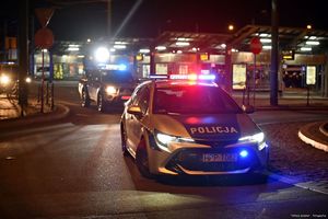 Na zdjęciu policyjne radiowozy z włączonymi sygnałami błyskowymi, które biorą udział w zabezpieczeniu przejścia kibiców na stadion.