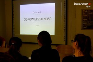 Na zdjęciu trzy złode osoby patrzące na wyświetlaną prezentację. Na wyświetlanym slajdzie napis o treści: co to jest odpowiedzialność?