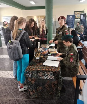 Na zdjęciu uczniowie szkoły mundurowej przy stoisku promocyjnym. Uczniowie ubrani są w szkolne mundury.