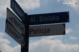 Na zdjęciu drogowskaz pokazujący nazwę ulic: Budowlanych oraz aleję Bielską, a także nazwę instytucji publicznych: Policja, Sąd Rejonowy oraz Wydział Komunikacji.
