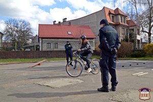 Na zdjęciu widać osobę jadącą rowerem oraz dwóch umundurowanych strażników miejskich.