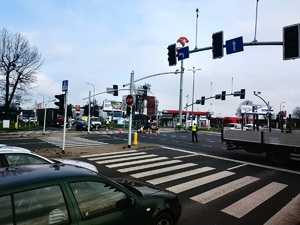 Na zdjęciu skrzyżowanie z sygnalizacją świetlną ulicy Oświęcimskiej, Mikołowskiej i Katowickiej w Tychach. Na środku skrzyżowania stoi umundurowany policjant ruchu drogowego, kierując ruchem.