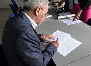 Na zdjęciu mężczyzna podpisujący dokument.