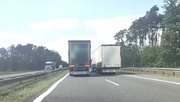 Na zdjęciu droga dwujezdniowa. Na prawym i lewym pasie ruchu jadące równolegle samochody ciężarowe.