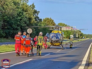 Na zdjęciu Lotnicze Pogotowie Ratunkowe oraz ratownicy i strażacy transportujący na noszach poszkodowanego.