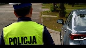Na zdjęciu  policjant w kamizelce odblaskowej stojący obok samochodu.