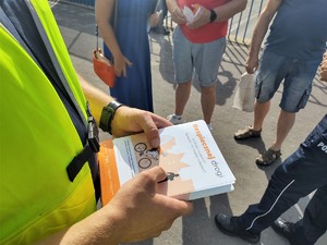 Na zdjęciu policjant trzymający ulotki pod nazwą Bezpiecznej Drogi.